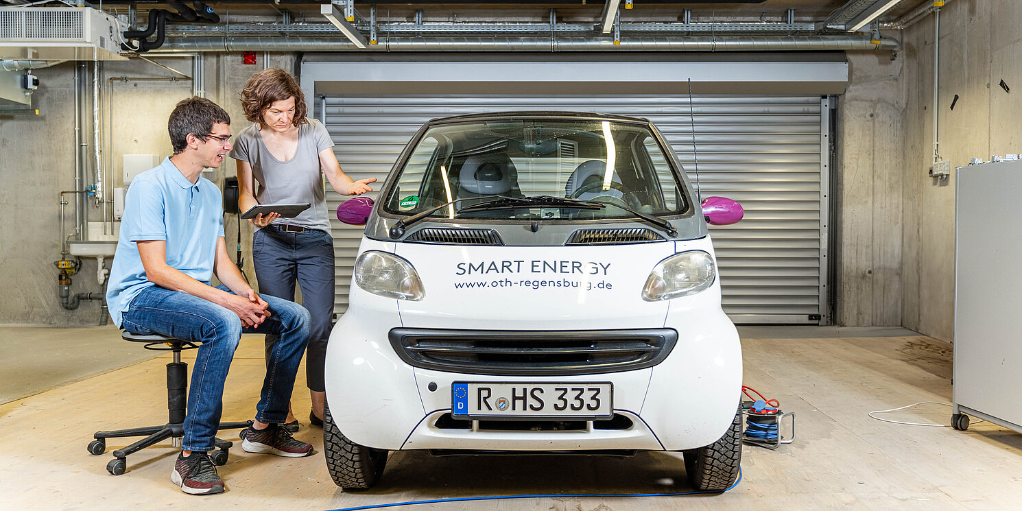Car IT und Elektronik berufsbegleitend studieren Zwei Studierende arbeiten an einem E-Auto.