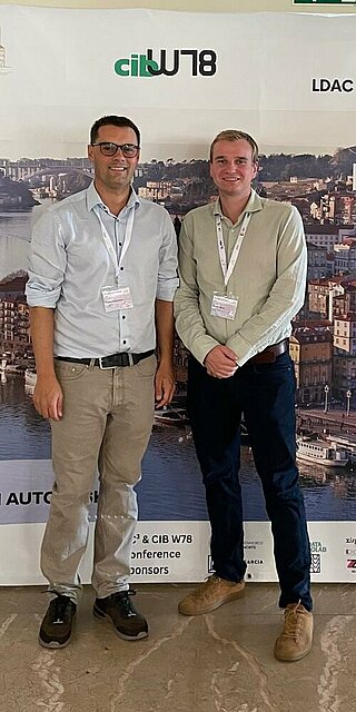 Zwei Personen stehen vor einer Pressewand der European Conference on Computing in Construction (EC³) in Porto. 
