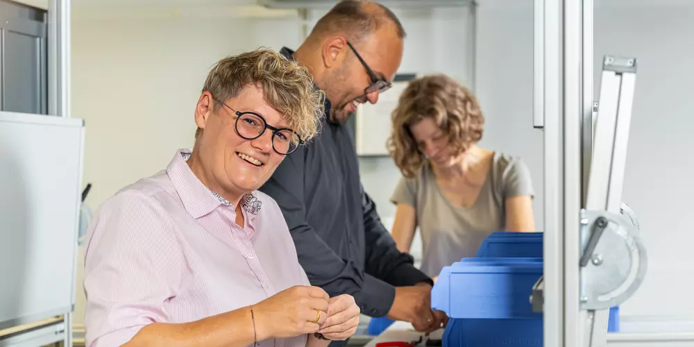 Drei Studierende arbeiten im LeanLab an einer Fertigungsstrecke. 