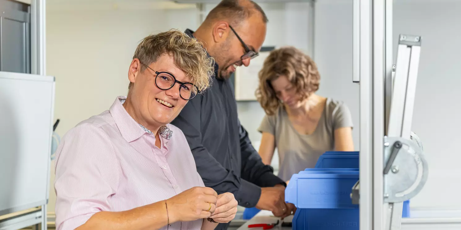 Fachseminar Low Cost Automation and Cardboard Engineering berufsbegleitend absolvieren Drei Studierende arbeiten im LeanLab an einer Fertigungsstrecke.