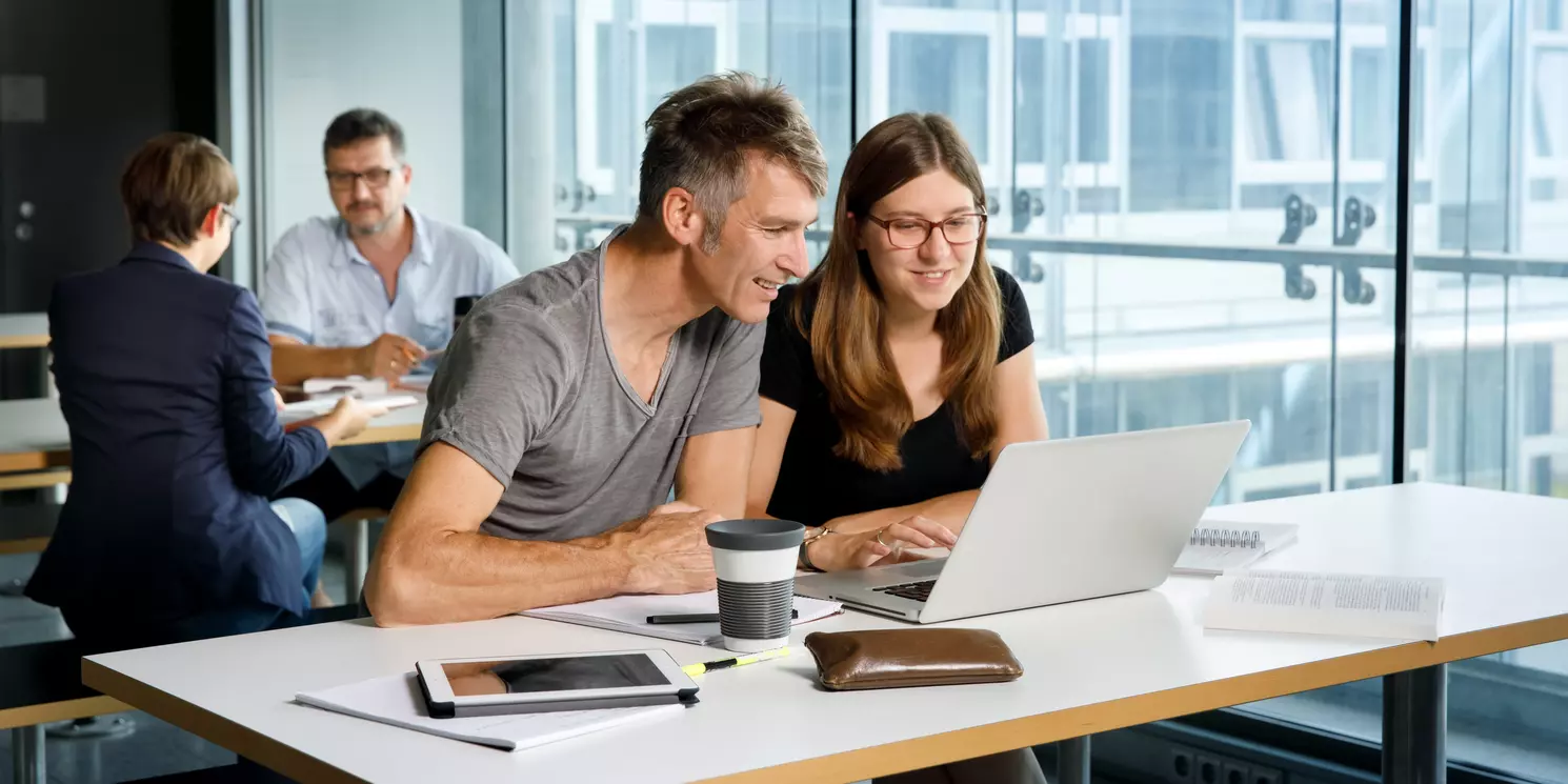Evidence Based Practice Pflege berufsbegleitend studieren Vier Studierende lernen und arbeiten an ihren Tischen mit Büchern und Laptops