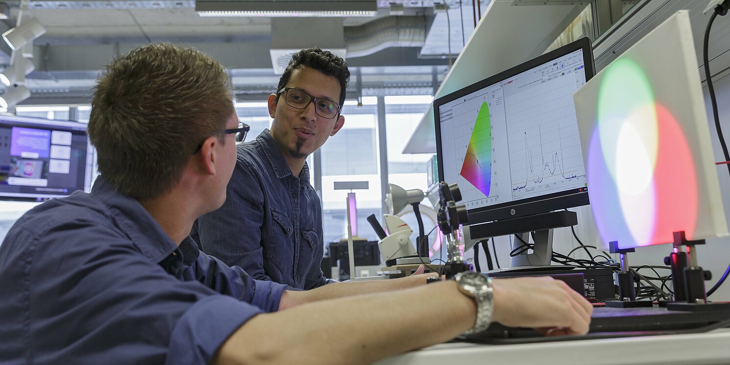 Zwei Studierende arbeiten an einem Versuchsaufbau.