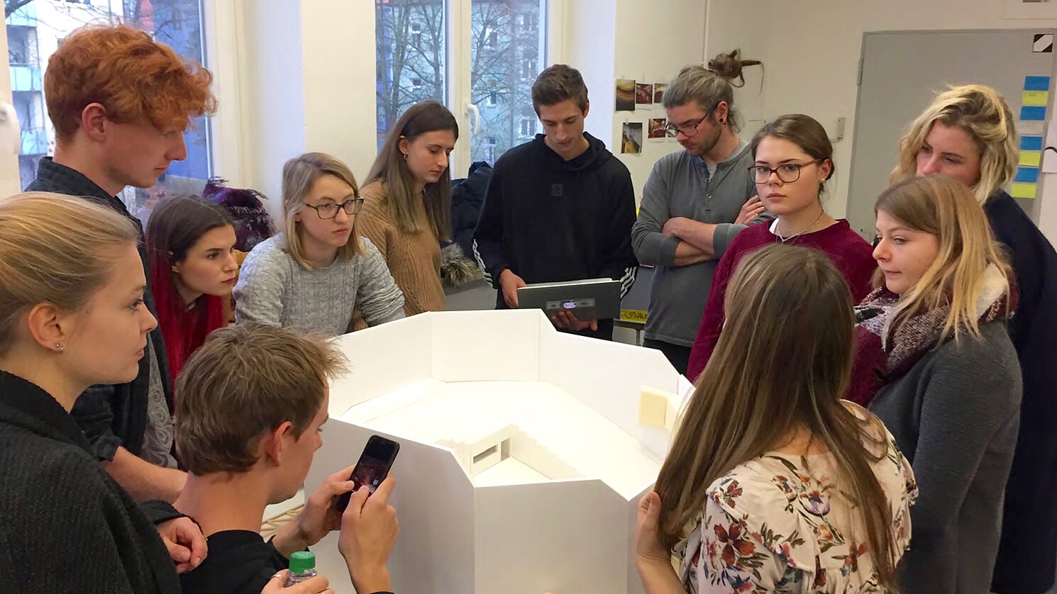 Ein Team mit Studierenden des Studiengangs Industriedesign der OTH Regensburg aus drei verschiedenen Semestern bespricht vor dem Modell des Audimax seinen Entwurf.