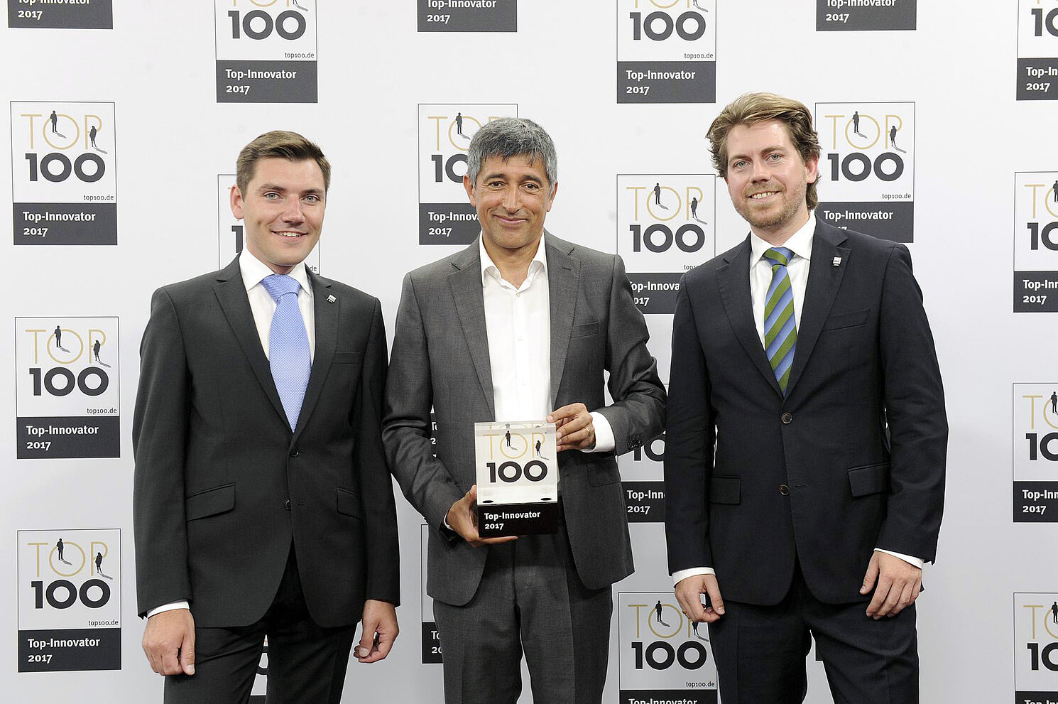 Josef Freundorfer (links) und Dr. Michael Deubzer (rechts, beide Timing-Architects Embedded Systems GmbH) freuen sich über die Auszeichnung TOP 100, die ihnen von Wissenschaftsjournalist Ranga Yogeshwar übergeben wurde. Foto: Timing-Architects