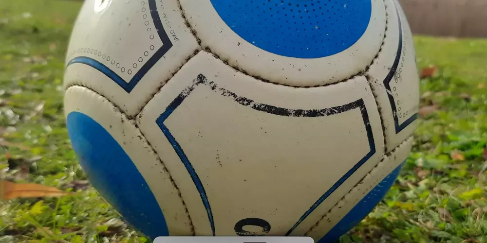 Die OTH Regensburg-Karte ist an einem Fußball angelehnt welcher auf dem sattgrünen herbstlichen Rasen liegt. Im Hintergrund ist der See vor den Gebäuden Mensa und Bibliothek zu sehen.