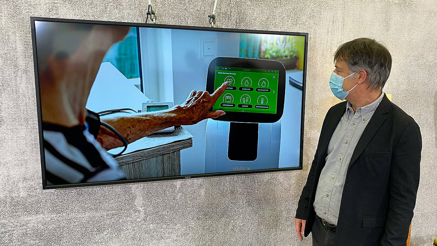 Prof. Dr. Karsten Weber, Projektleiter TePUS, zeigt mit Monitoren ausgestatte Assistenzsysteme.