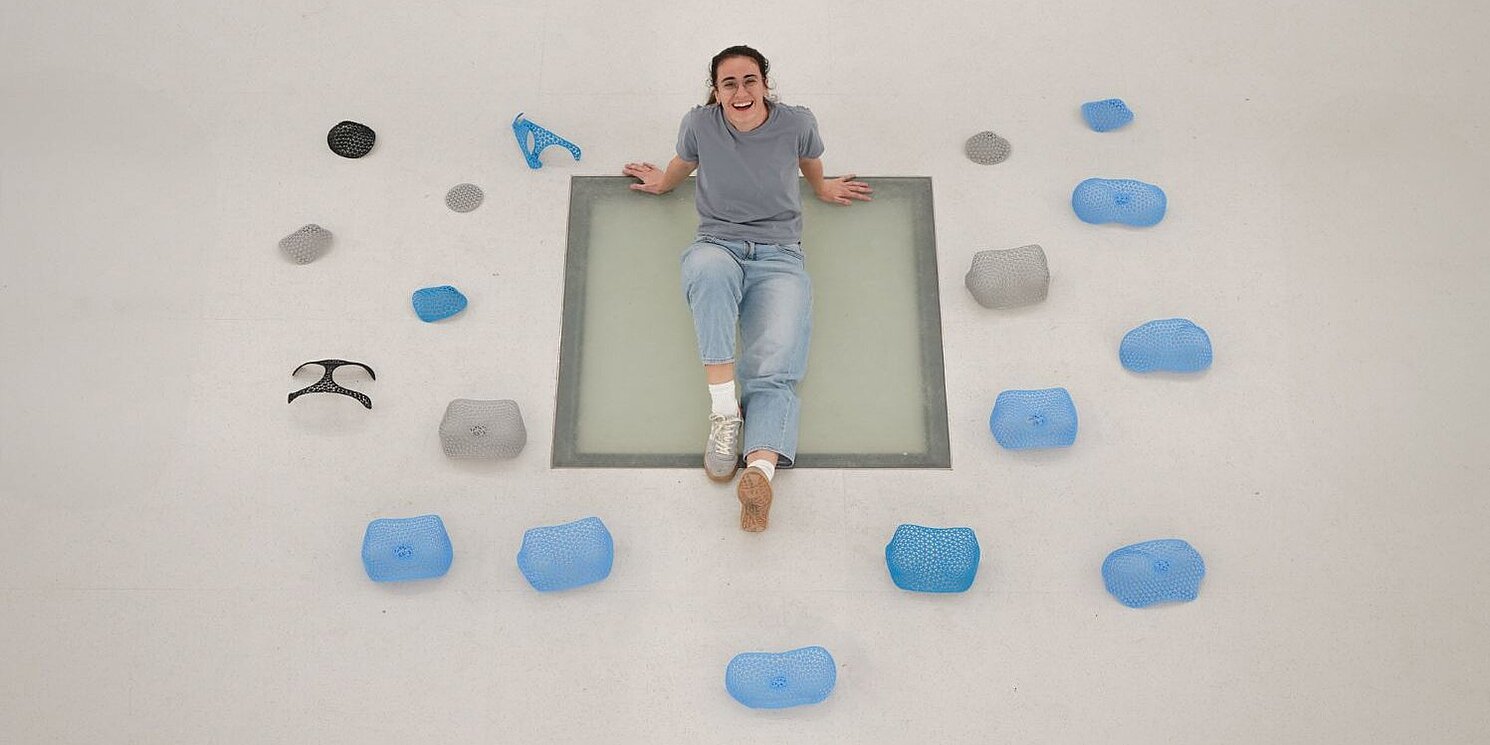 Beatriz Jerez Arnau liegt auf dem Boden um sie herum verschiedene Brustschutzschalen in blau und grau. 