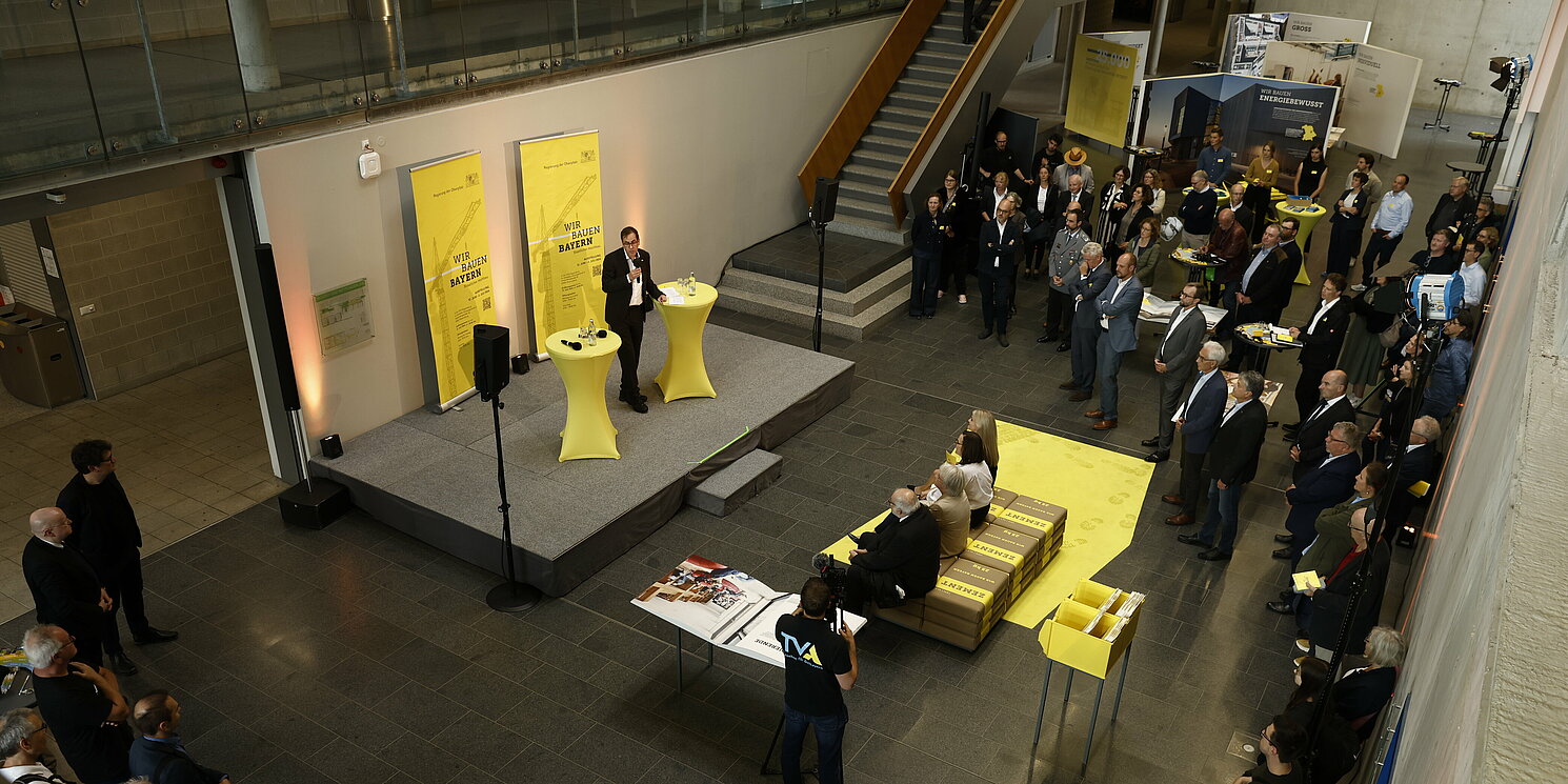 Blick von oben in eine Foyer mit einer Bühne und Stellwänden.