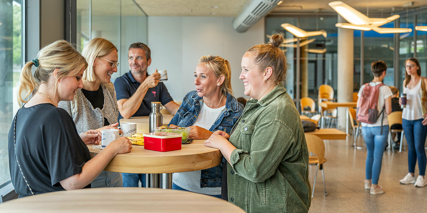 Studierende unterhalten sich in der Cafeteria.