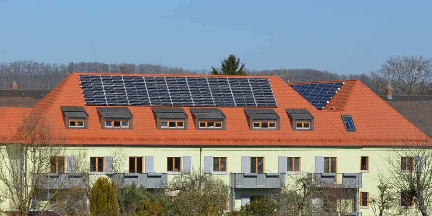 Zu sehen sind die modernisierten Wohngebäude im Wohnquartier Margaretenau. Auf den Dächern befinden sich Photovoltaik-Anlagen