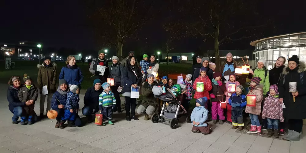 Eine Gruppe von Eltern und Kindern stehen mit ihren Laternen vor den OTH Gebäude.