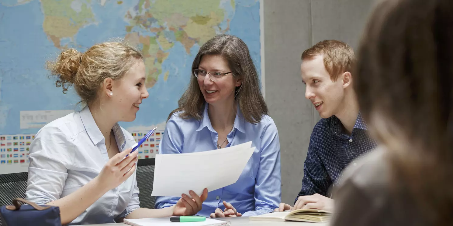 Dozentin mit Studierenden an Tisch