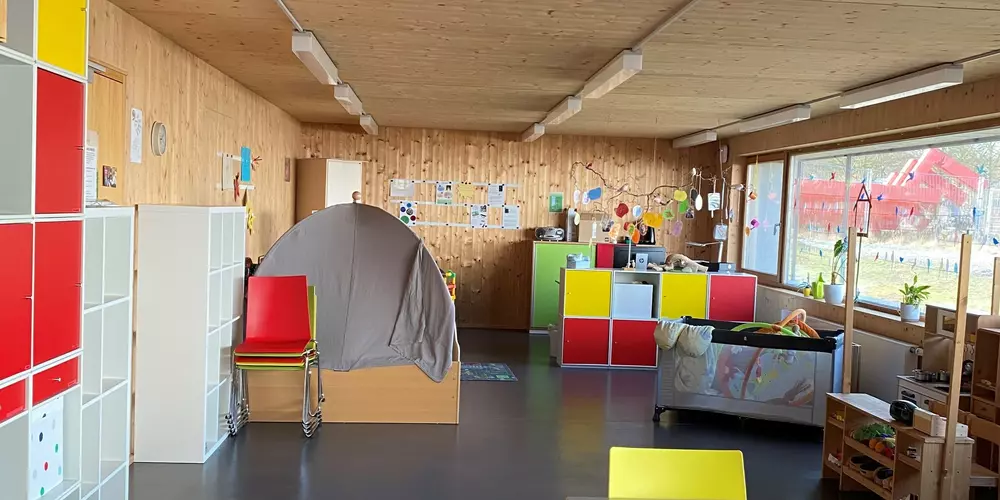 Ein Raum mit bunten Schränken, Spielmöglichkeiten und einem Kinderbett.