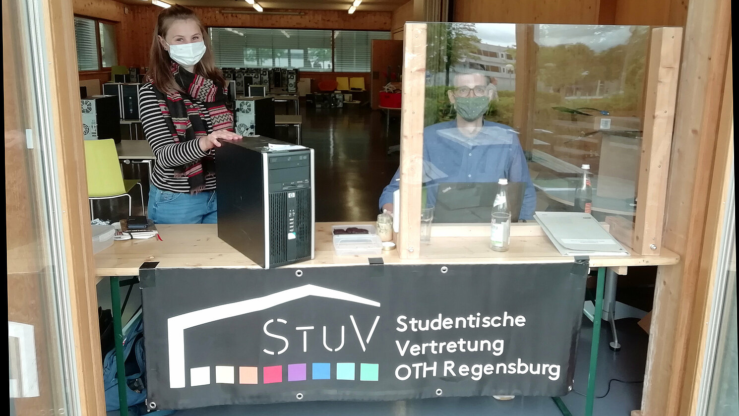 Regina Griesbeck und Liam McNeilly, Mitglieder der Studierendenvertretung der OTH Regensburg, bei der Ausgabe der Rechner und Laptops an Studierende.