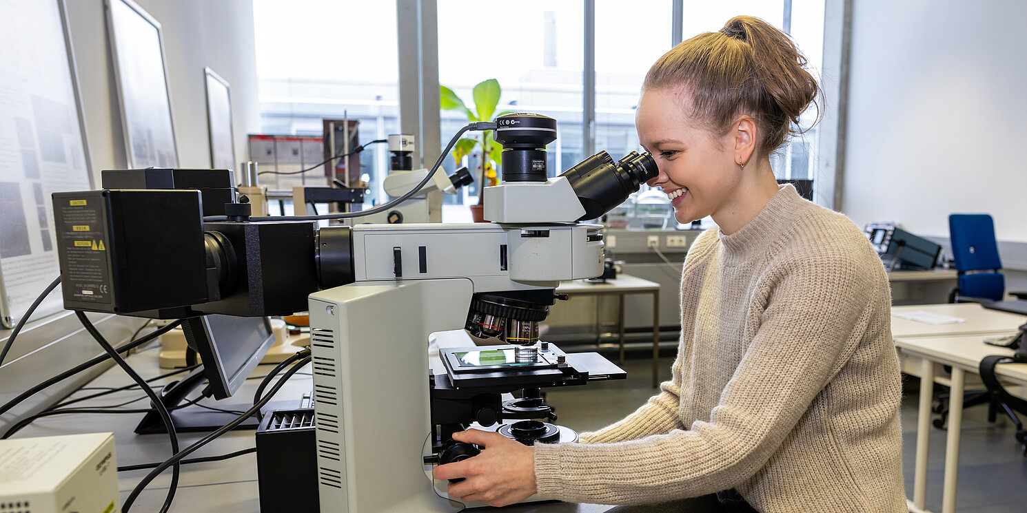 Studentin im Labor Biomaterialien bei der Arbeit an einem Mikroskop