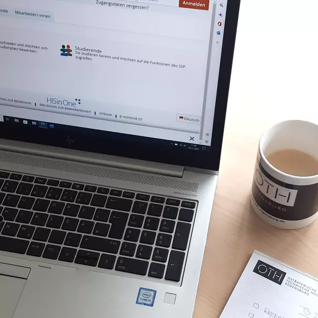 The photo shows a table with a computer and a cup of coffee. Notes are being taken on a block in preparation of the application.