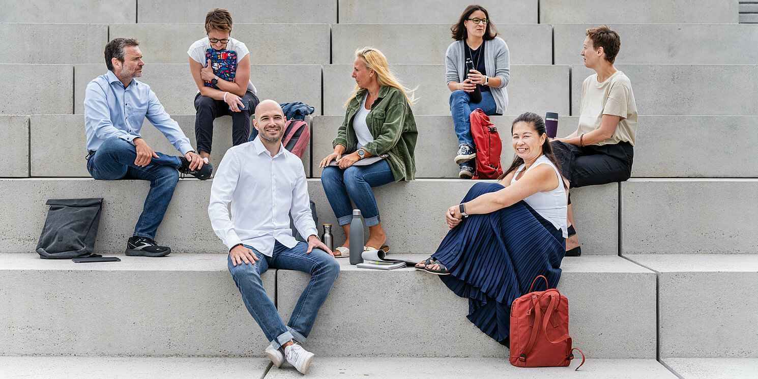 Zentrum für Weiterbildung und Wissensmanagement Mehrere Studierende sitzen mit ihren Lernmaterialien auf einer großen Treppe.