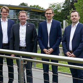 Fünf Männer stehen auch einer Brücke und schauen zur Kamera.