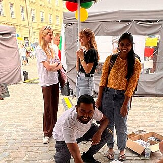 Mehrere Personen stehen unter einen Pavillon um eine große Weltkarte herum.