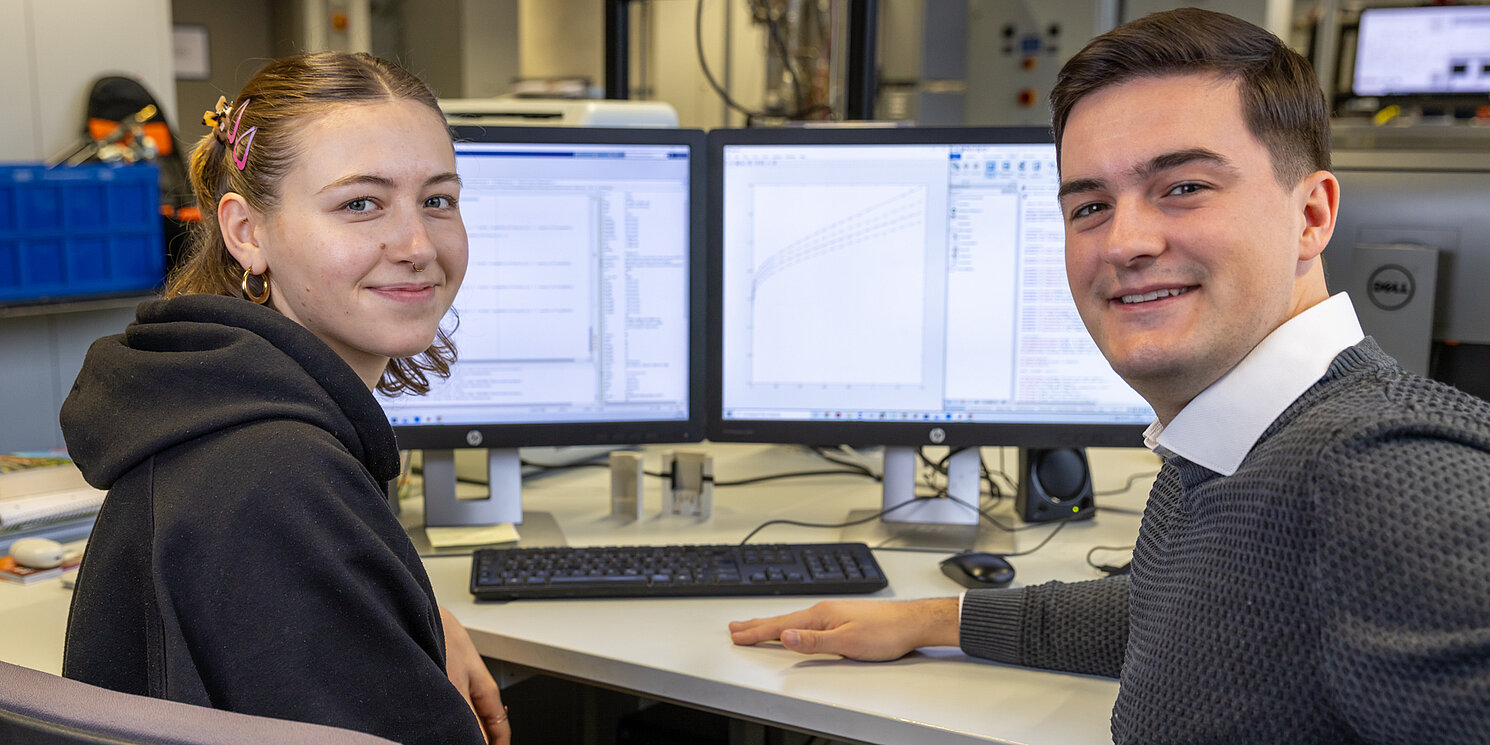 Zwei Studierenden arbeiten vor einem PC im Labor.