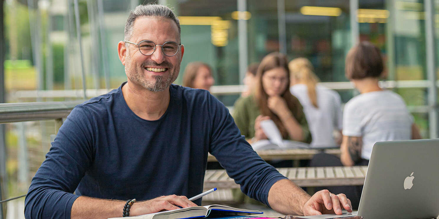 Studierende auf einem Steg über dem Mensa-See lernen an Arbeitsplätzen