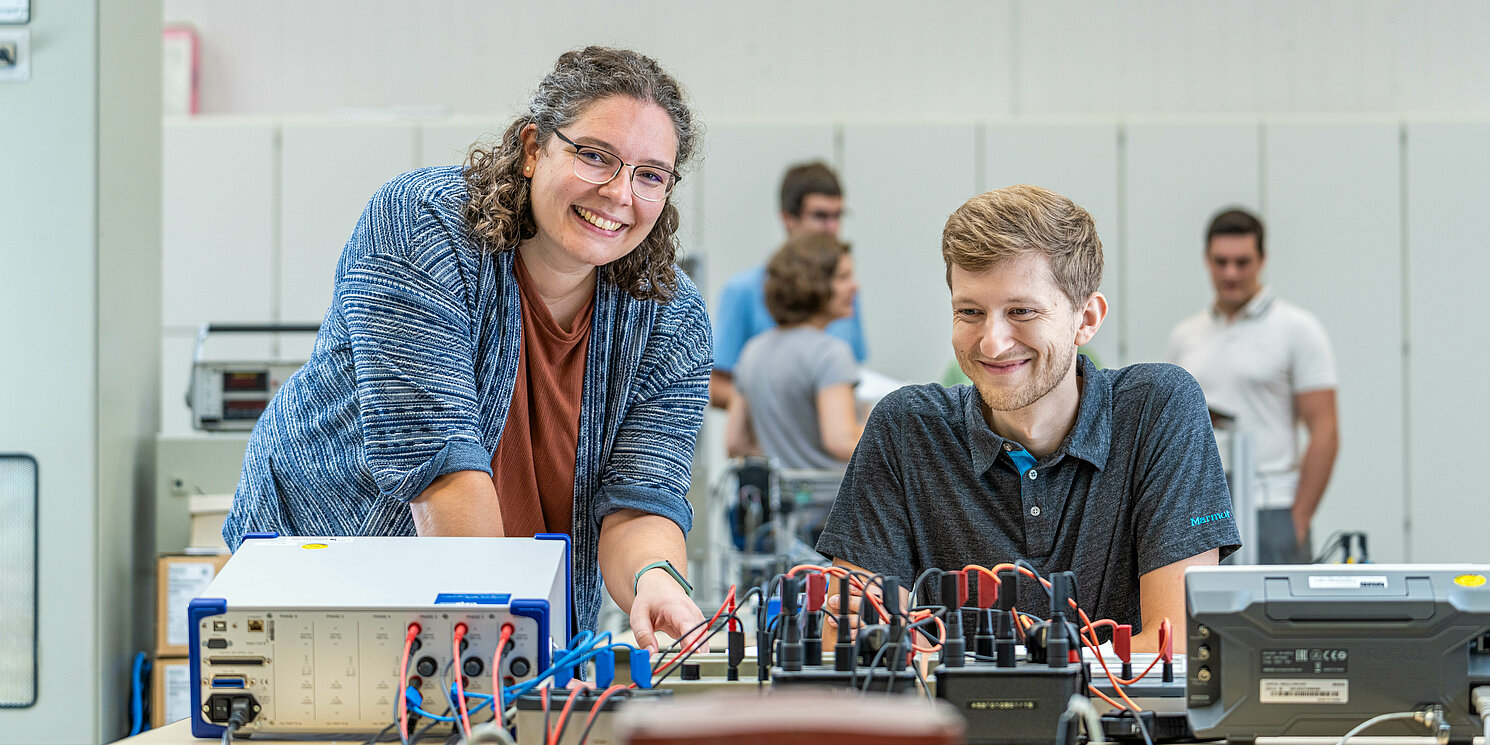 Zwei Studierende arbeiten in einem Labor an einem elektronischen Schaltkasten.