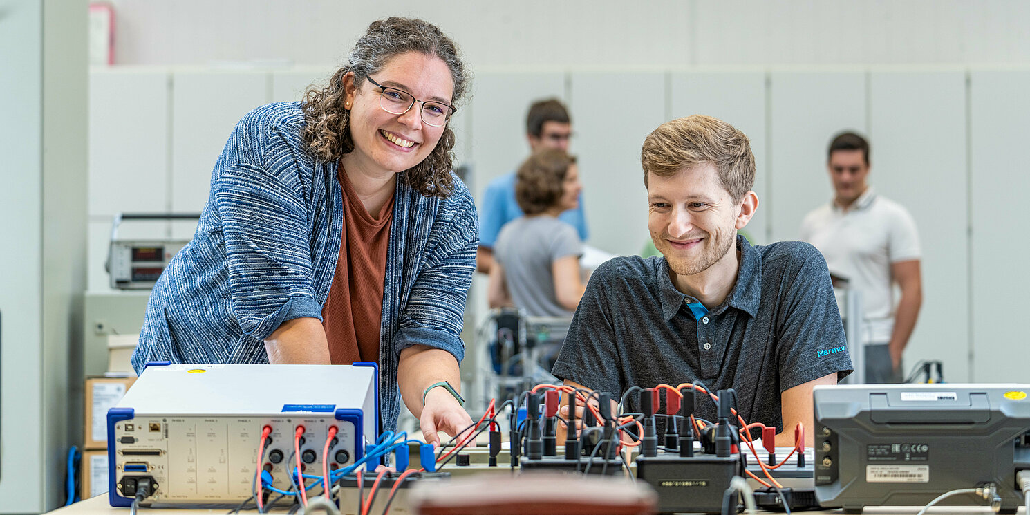 Automotive Electronics berufsbegleitend studieren Zwei Studierende arbeiten in einem Labor an einem elektronischen Schaltkasten.