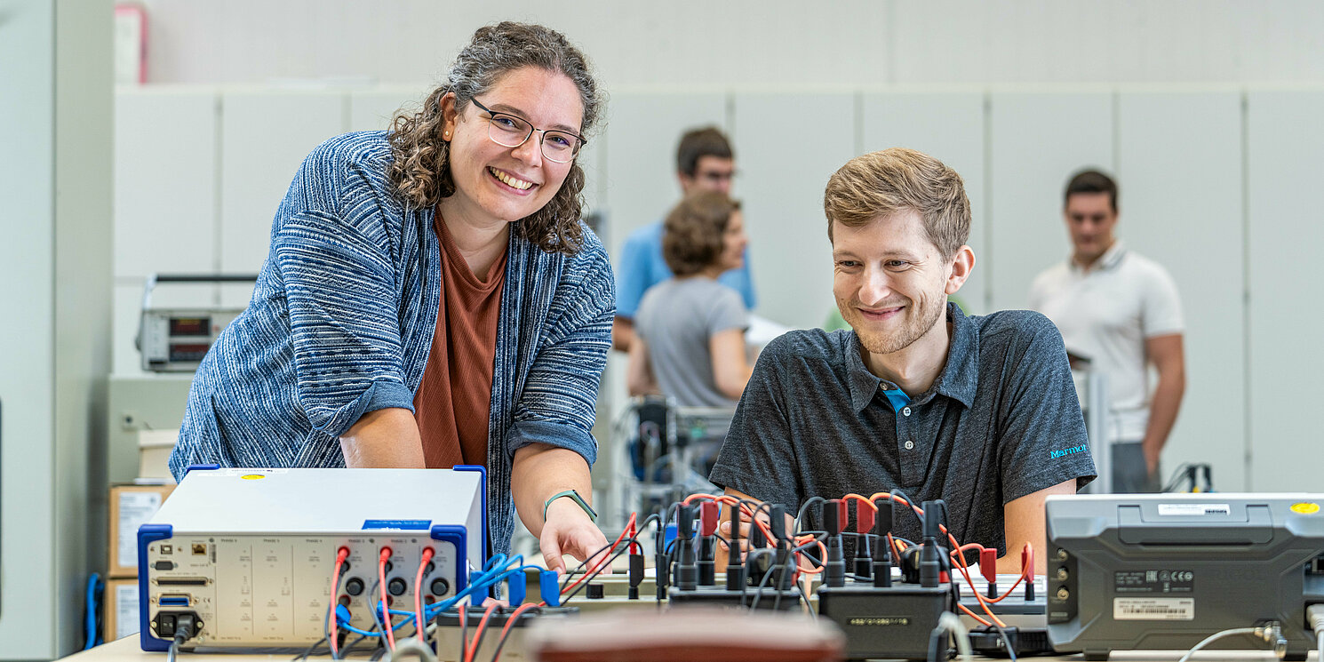 Zwei Studierende arbeiten in einem Labor an einem elektronischen Schaltkasten.
