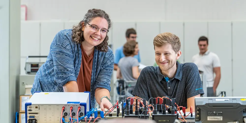 Zwei Studierende arbeiten in einem Labor an einem elektronischen Schaltkasten.