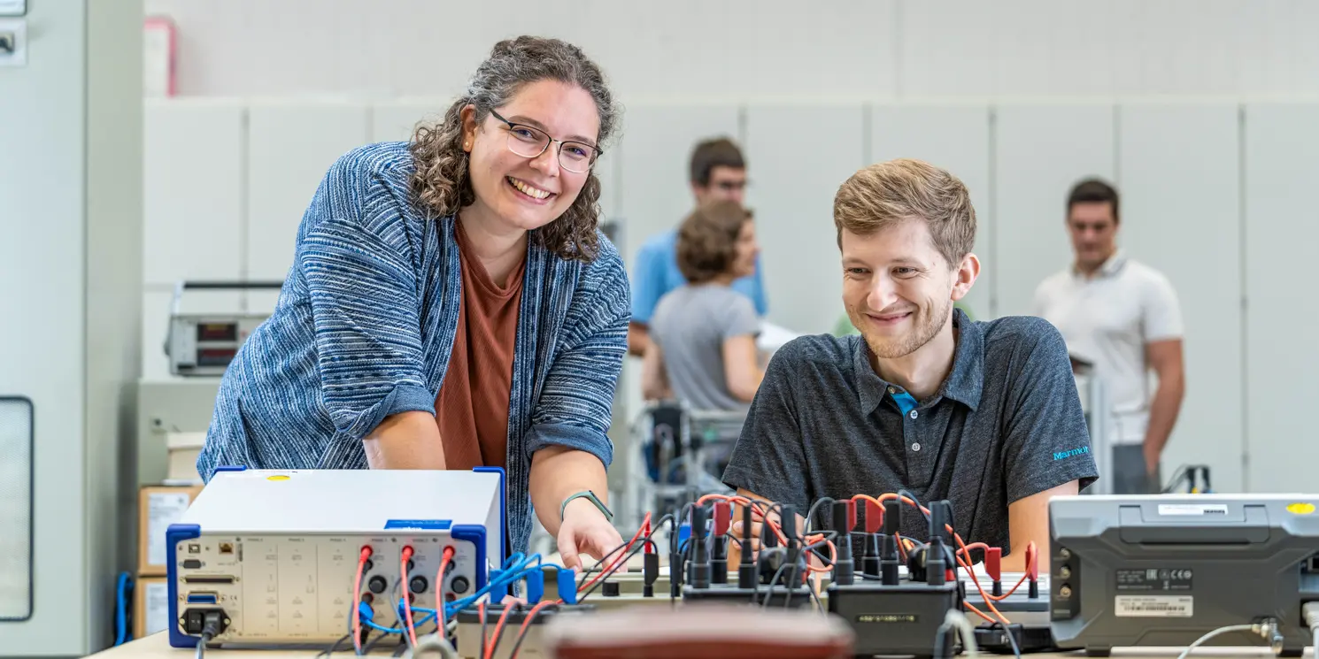 Car IT und Elektronik berufsbegleitend studieren Zwei Studierende arbeiten in einem Labor an einem elektronischen Schaltkasten.