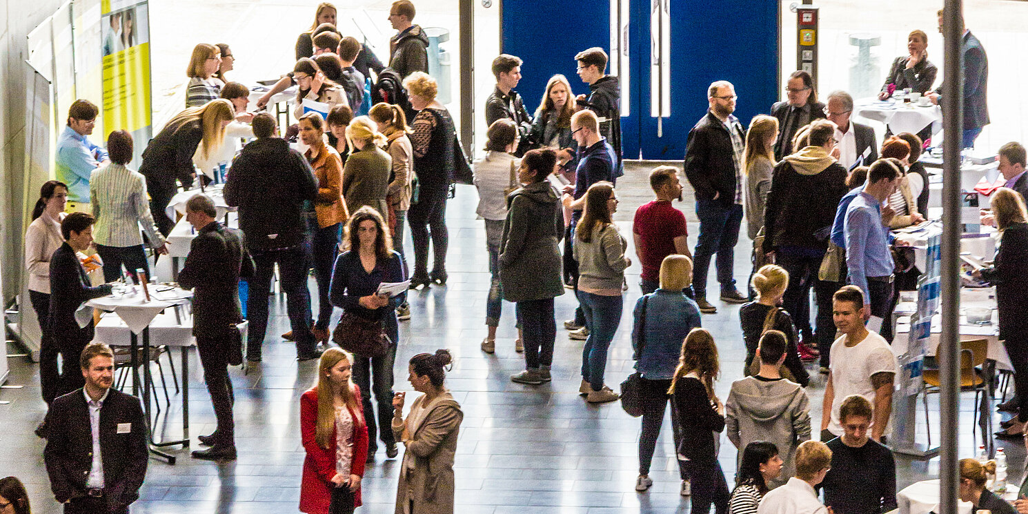 Tag der offenen Hochschule Foyer mit Messe-Ständen und vielen interessierten Besucher:innen