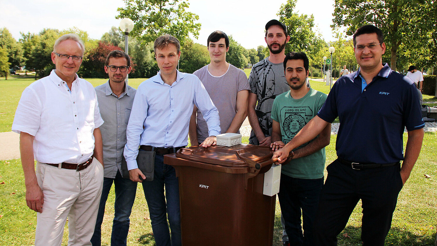Die „intelligente“ Abfalltonne mit Verantwortlichen: (von links) Prof. Dr. Martin Schubert, Josef Weiß, Prof. Dr. Jan Dünnweber, Markus Wildgruber, Vadim Dechand, Haris Shehzad und Konstantin Hendrik Kirsch von KPIT. Foto: Diana Feuerer