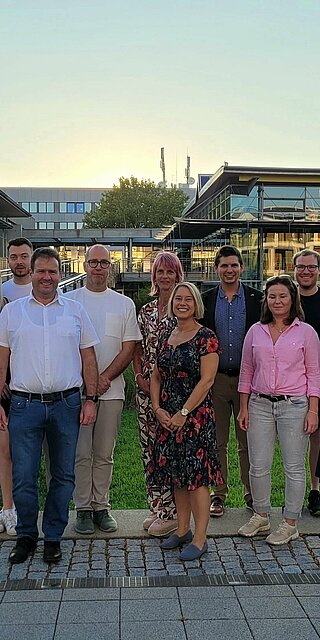Eine Gruppe Menschen steht vor dem Mensa- und Bibliotheksgebäude der OTH Regensburg