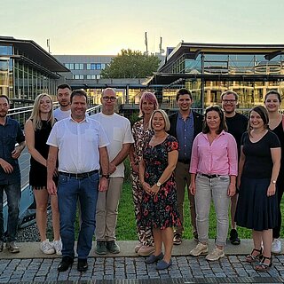 Eine Gruppe Menschen steht vor dem Mensa- und Bibliotheksgebäude der OTH Regensburg