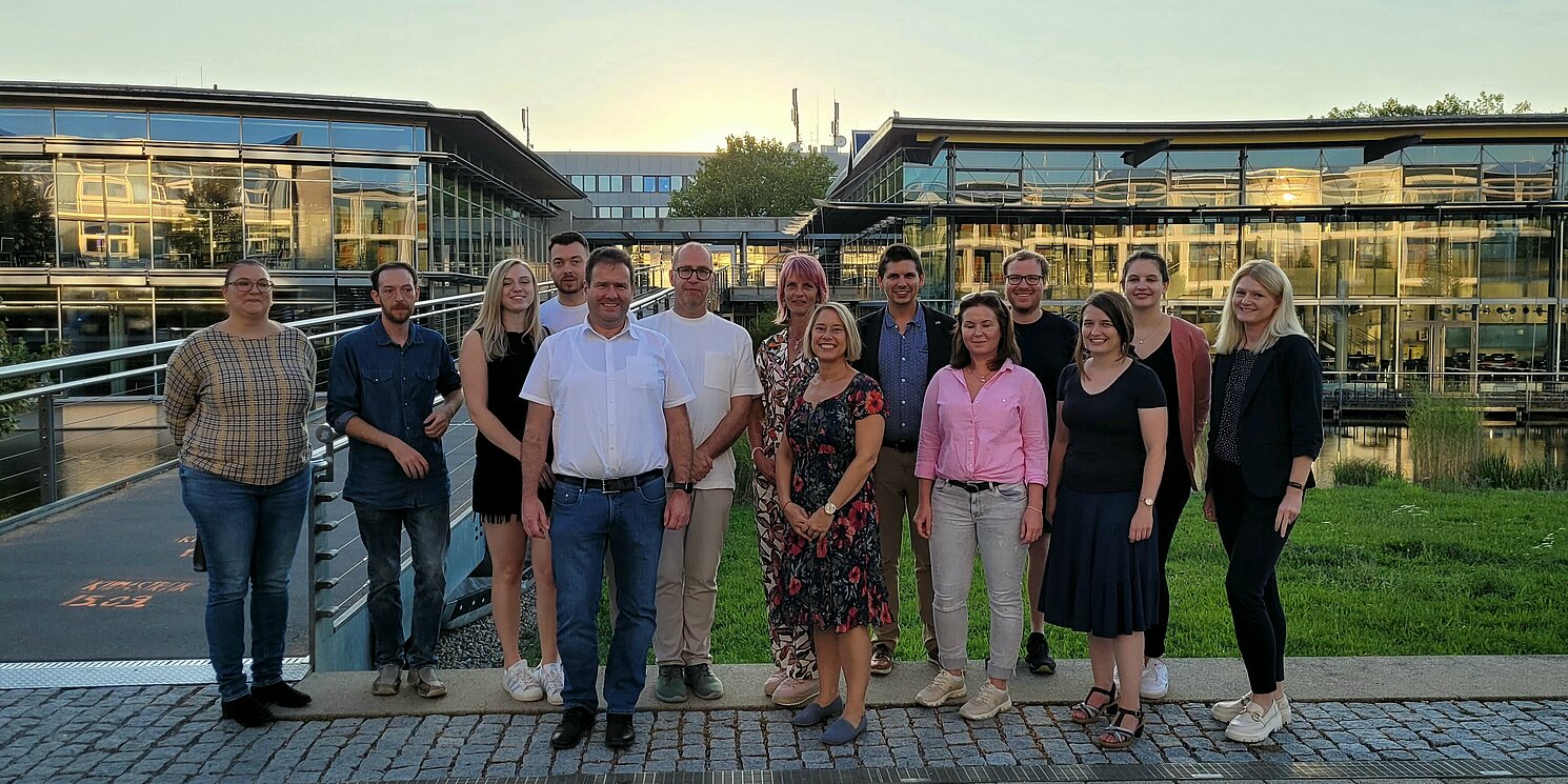 Eine Gruppe Menschen steht vor dem Mensa- und Bibliotheksgebäude der OTH Regensburg