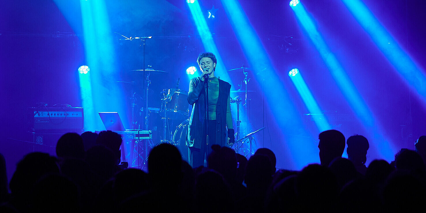 Eine Sängerin steht auf einer Bühne im Rampenlicht.