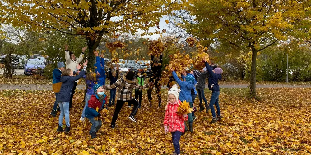 Eine Gruppe von Kindern spielt mit Herbstlaub.