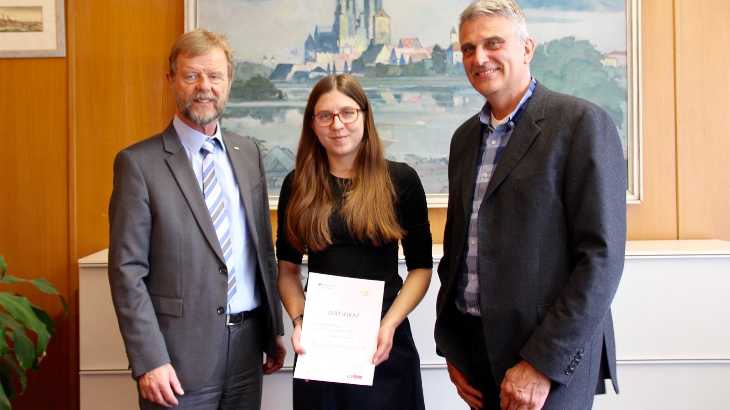 Von links: Der Präsident der OTH Regensburg Prof. Dr. Wolfgang Baier überreicht der Forschungsreferentin am IAFW, Susanne Deisböck, das EU-Zertifikat zusammen mit Prof. Dr. Thomas Falter, der Wissenschaftlicher Leiter am IAFW ist.